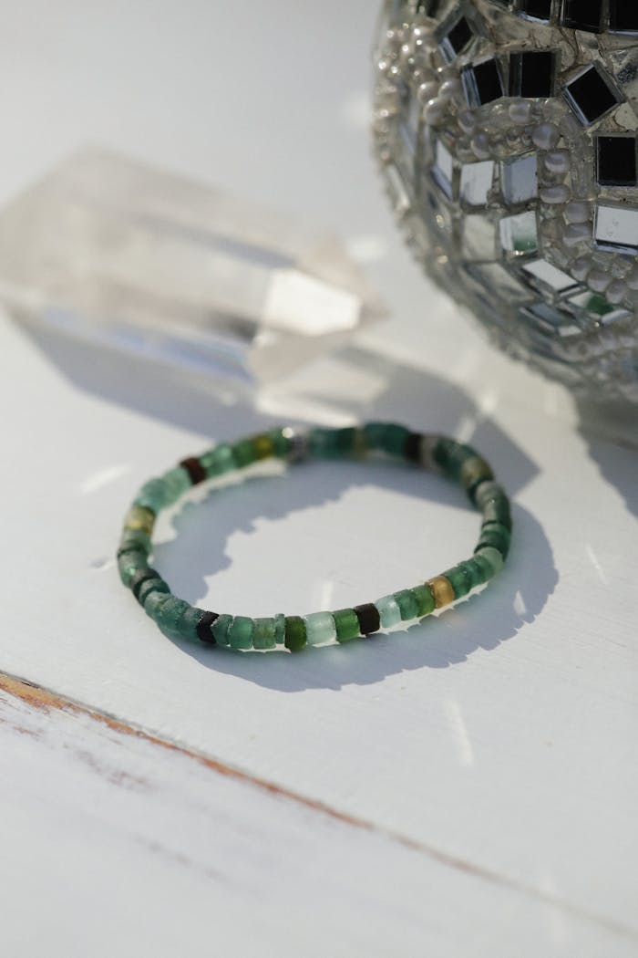Close-up of an elegant beaded bracelet displayed on a wooden surface with decorative glass