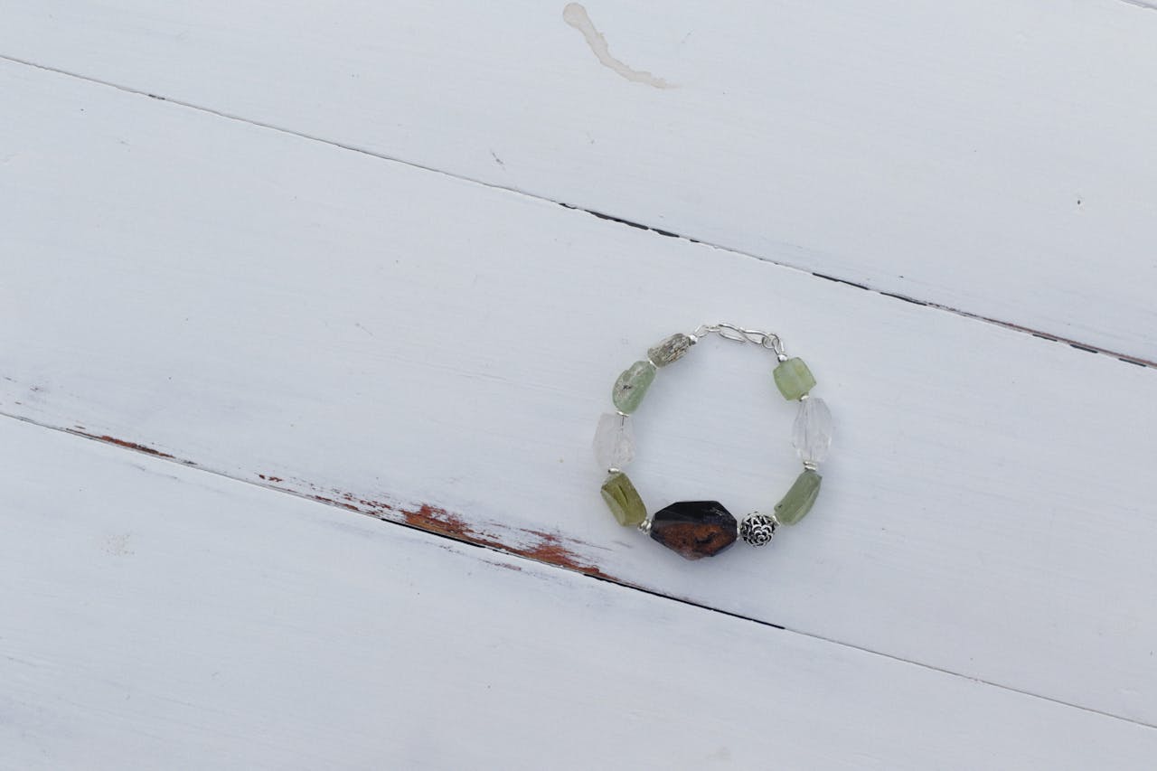 A stylish crystal bracelet with jade and colored beads on a rustic wooden surface.