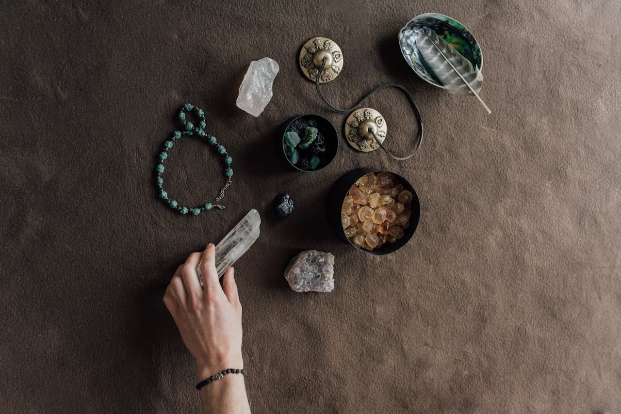 Hand arranging spiritual tools and crystals on a natural brown cloth surface.