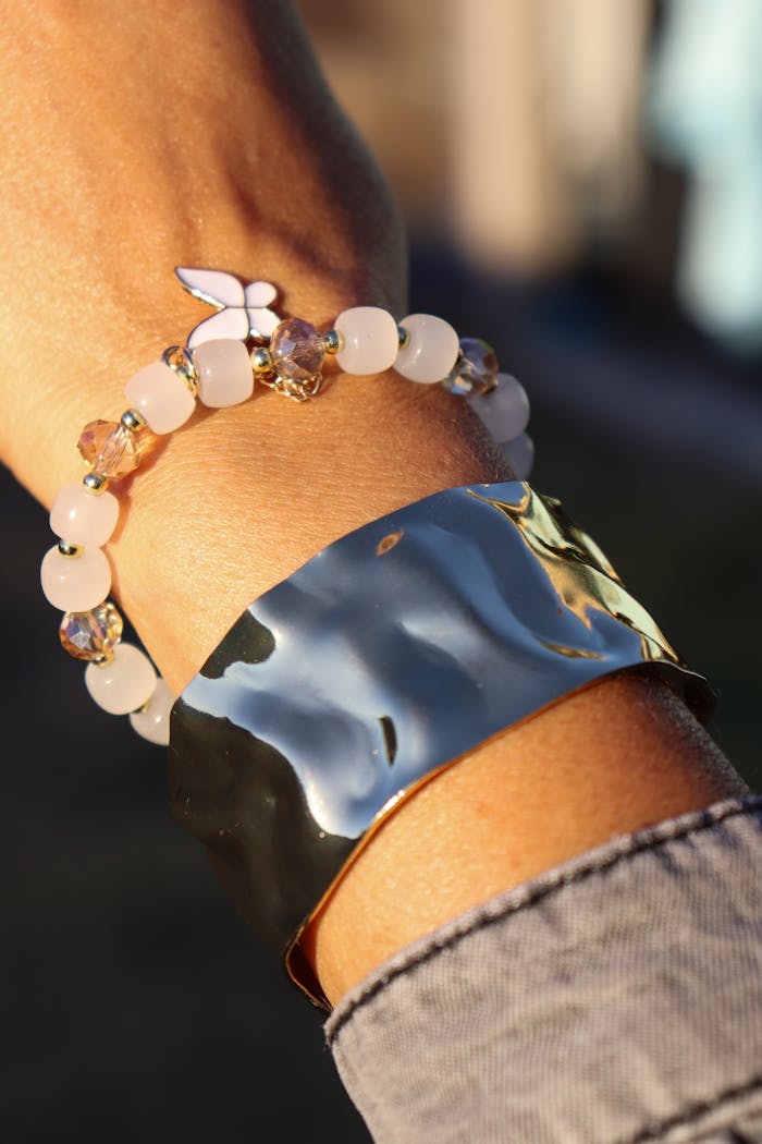 Elegant bracelet and shiny metal bangle on wrist in natural light, showcasing fashion accessories.